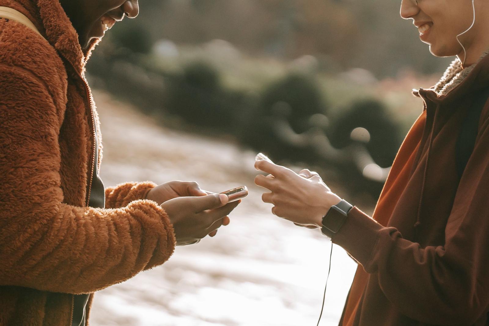 Crop Delighted Multiethnic Young Men Chatting on Modern Cellphones in City Street